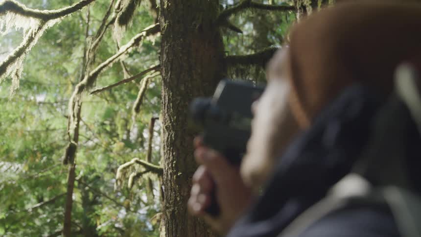 Male photographer makes a video in the woods