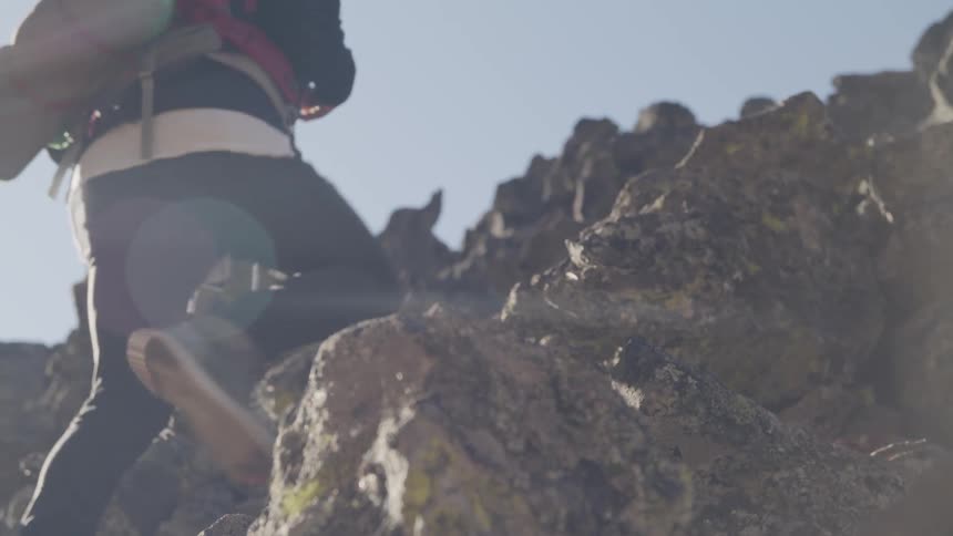White man with backpack climbing rocks