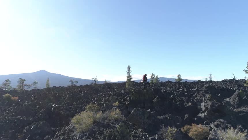 A teenager stands on top of a rock and looks out across the horizon
