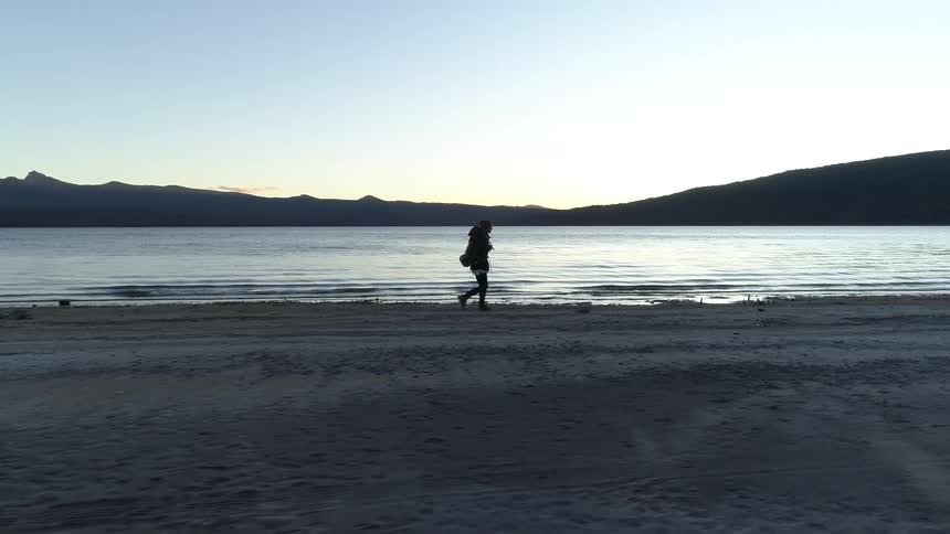 Man with backpack walking next to the lake