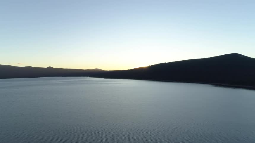 The sun rising behind a lake