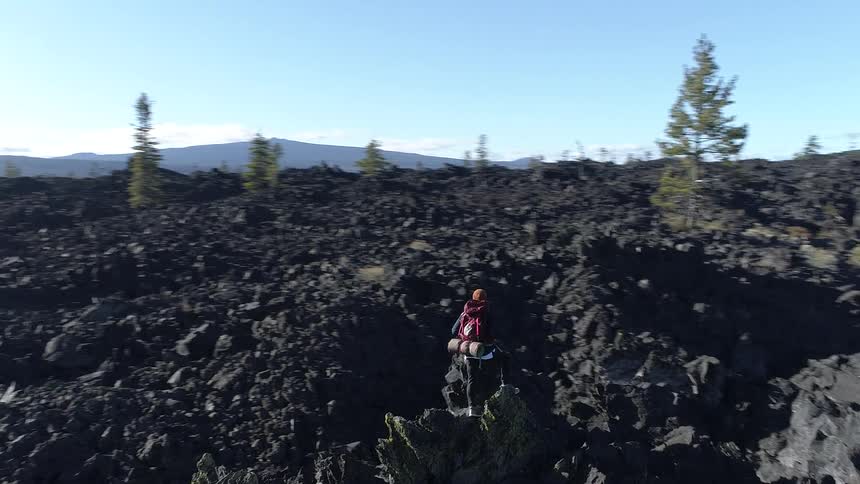 A hiker stands on the rocks looking over the horizon