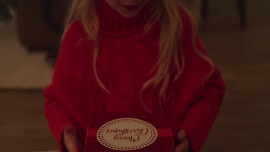 A small female child opening up a gift in surprise