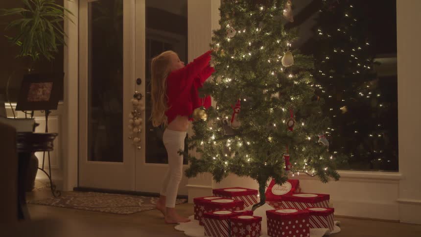 A girl puts an ornament on the christmas tree