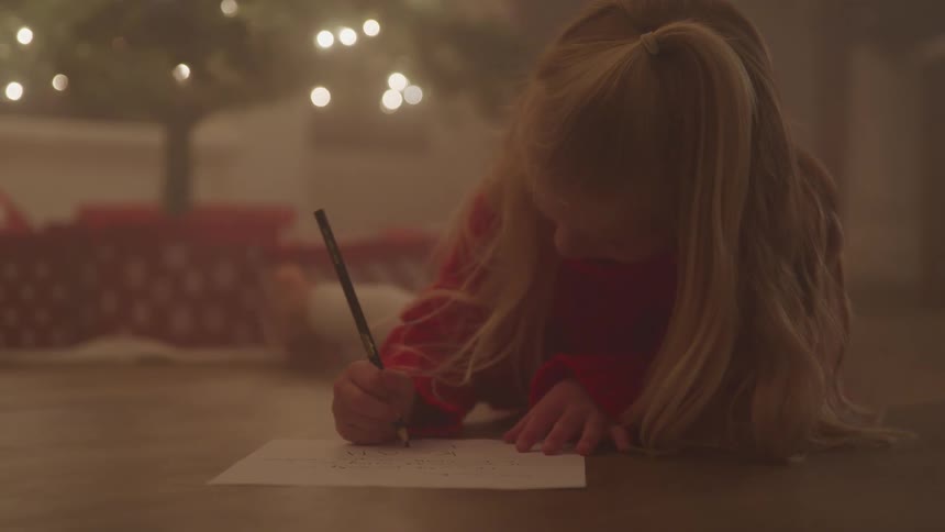 White girl drawing on a paper while laying on the floor