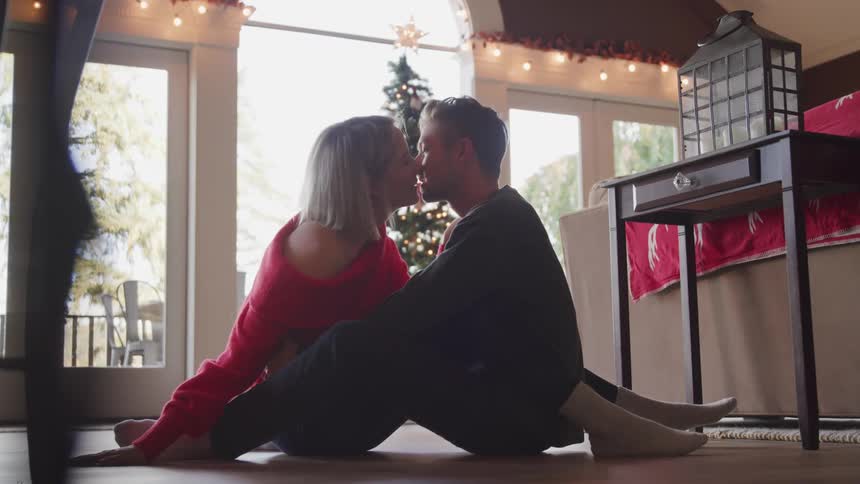 A couple kiss as they sit on the floor