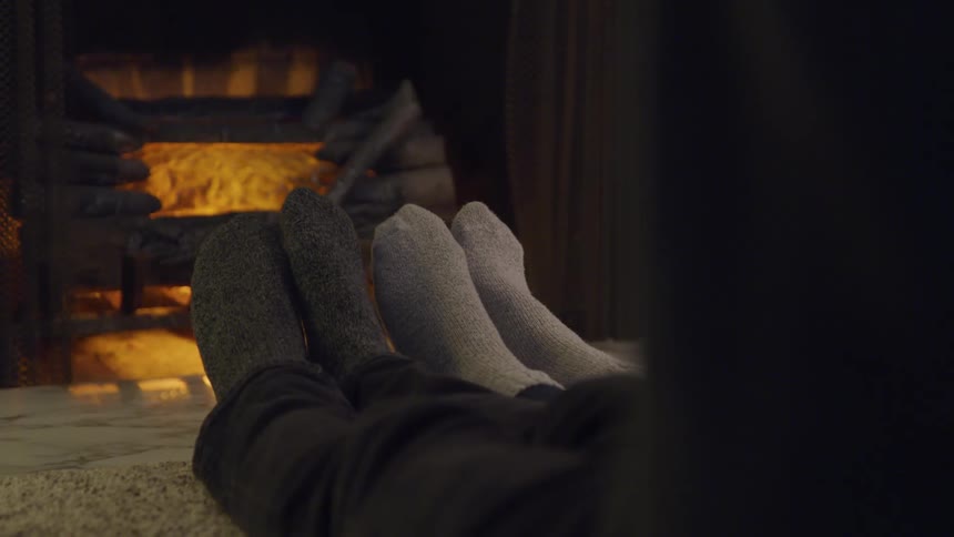 Close up of socked feet relaxing in front of fireplace