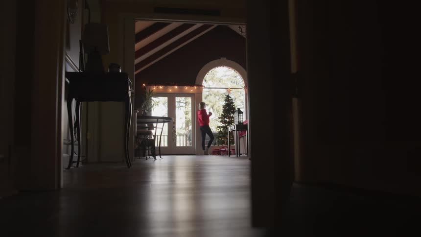 A woman walks to the window and drinks