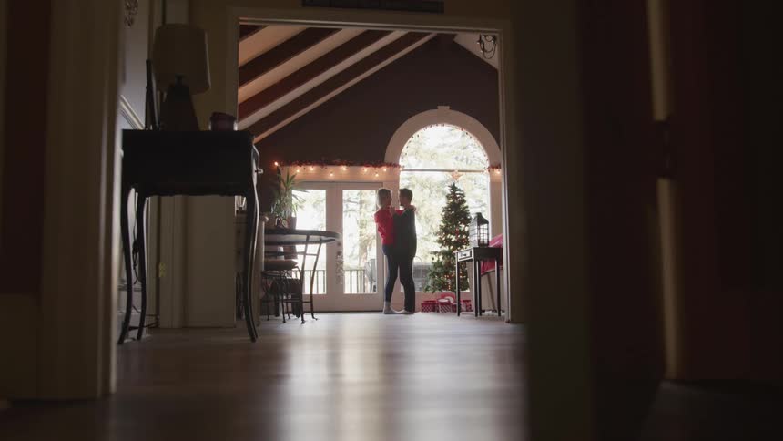 Husband and wife dance next to the christmas tree in the living room at home