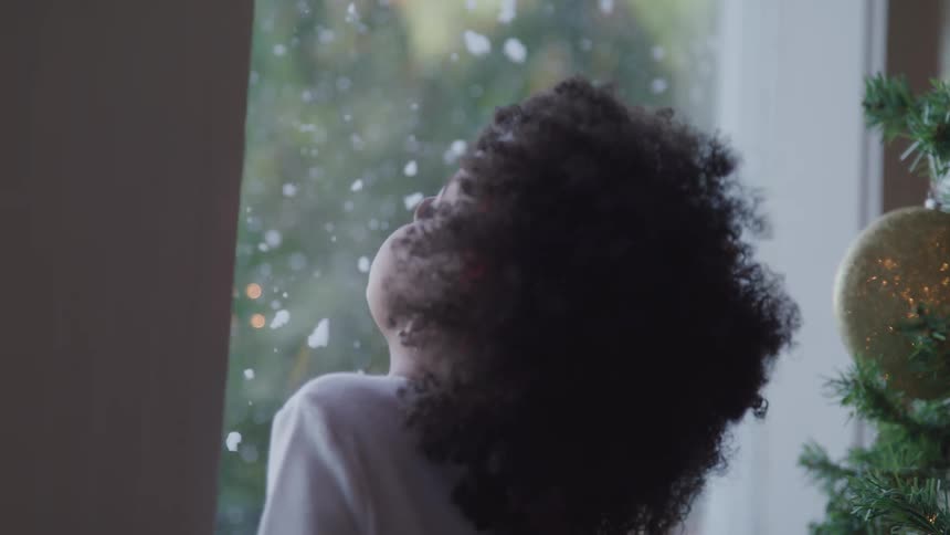 A child looking out of the window at falling snow
