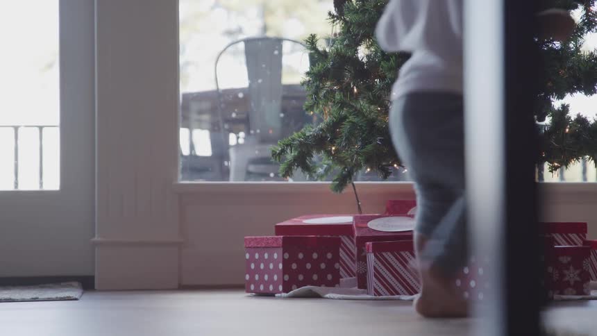 Toddler black child walks around the christmas tree in the living room at home