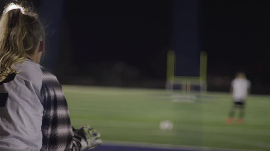 A female soccer players stands inside the goal waiting for another player to take a shot