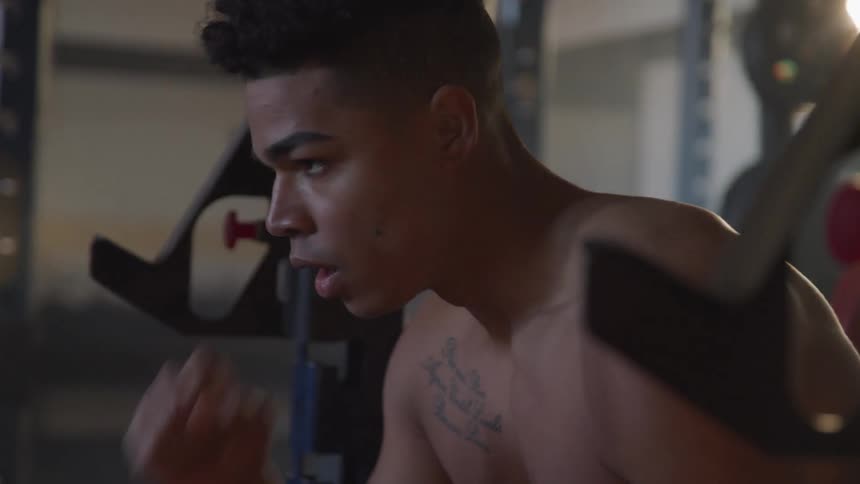 A black teenager prepares to lift weights in a gym