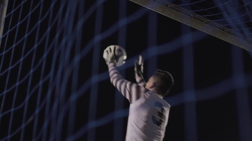 Soccer player jumps up and catches the soccer ball