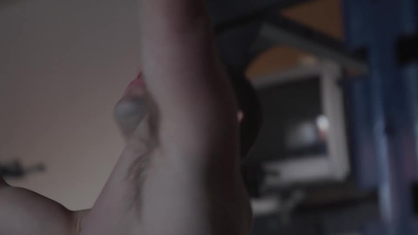 Shirtless muscular man pulls up in the gym