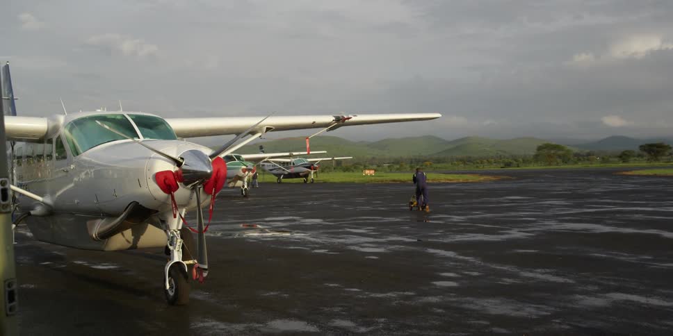 Small planes and airport workers on a cloudy day