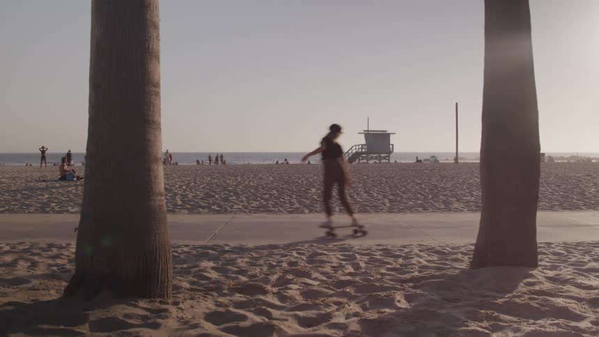 Young woman skating through a sidewalk in front of a beach