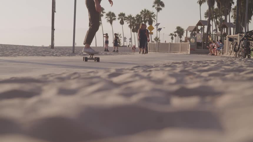 People skateboard and walk down a beach boardwalk