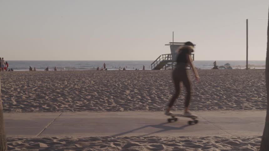 Woman skating at sidewalk in front of a beach