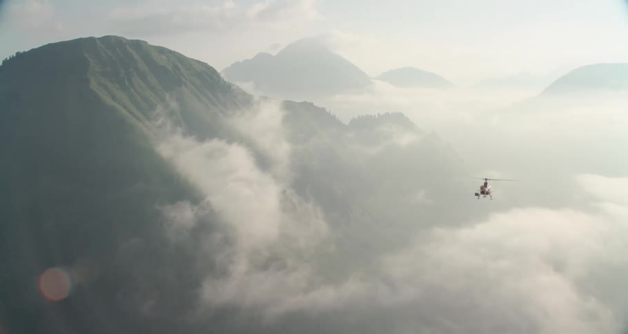 A helicopter flies through the mountains