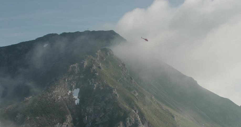 A helicopter flies over a mountain