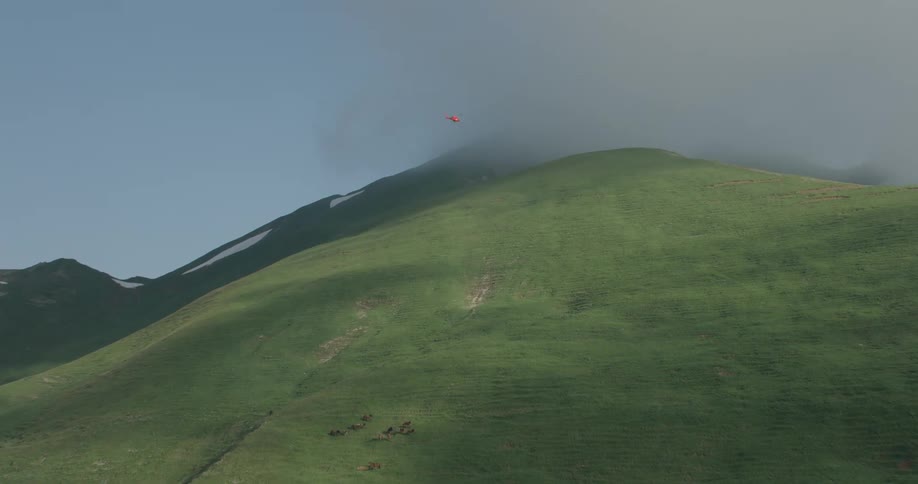 A helicopter flies over the hills
