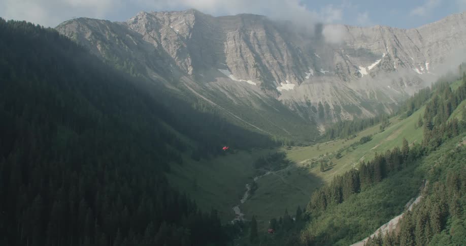 A helicopter flies through a mountain valley