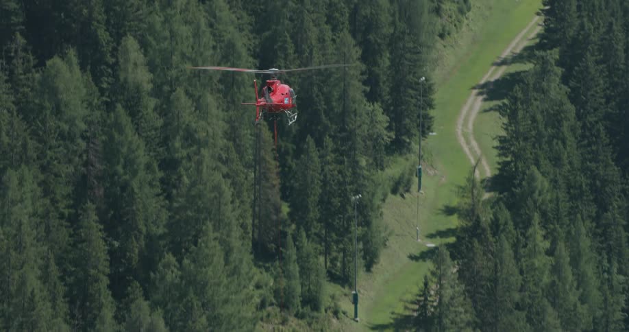 A medical helicopter flies over a forest