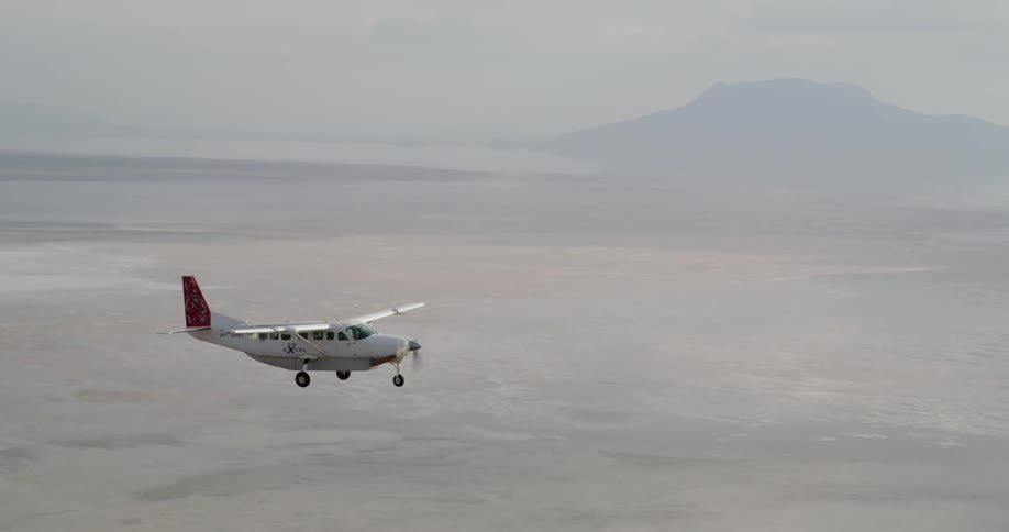 Small plane flies with a mountain in the distance