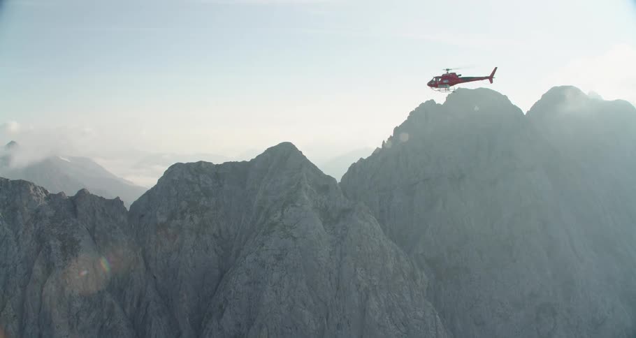 A helicopter flies over mountains