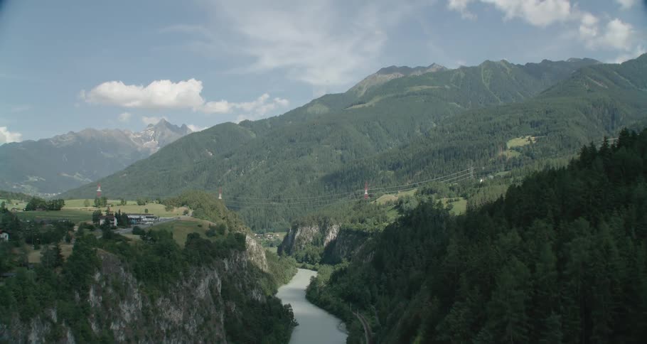 An aerial view of a mountain and forest is displayed near a river