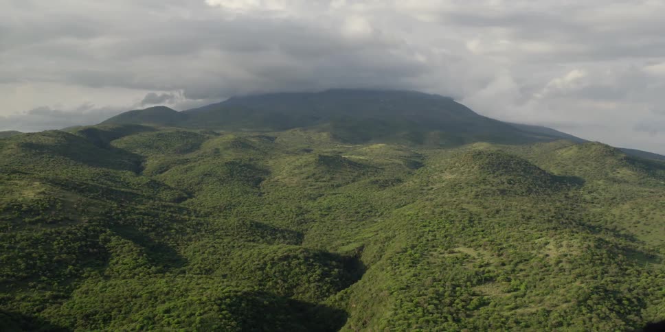 Clouds float over green hilly mountains