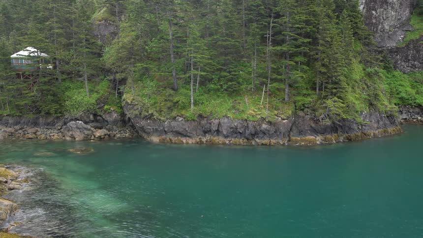 A blue green river through a forest on a rainy day