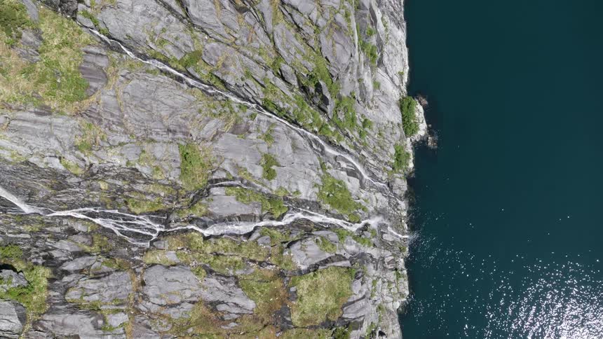 Waterfalls flow down a cliff into an ocean