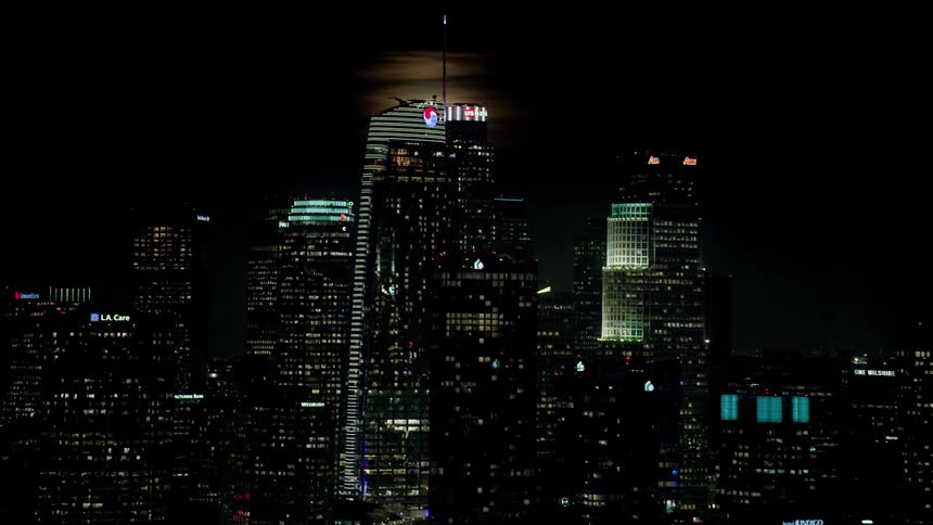 Aerial of full moon behind skyline in a metropolis area