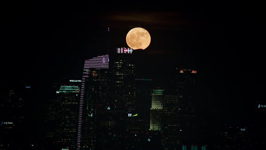 The moon hangs over a city