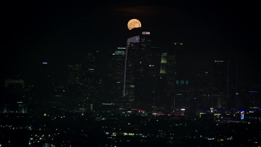A city skyline with the moon in the background