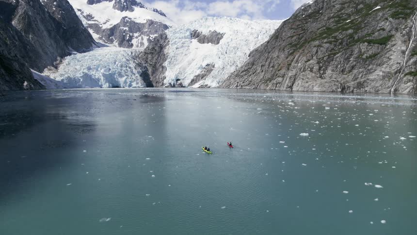 Three people use two kayaks to travel in an arctic ocean