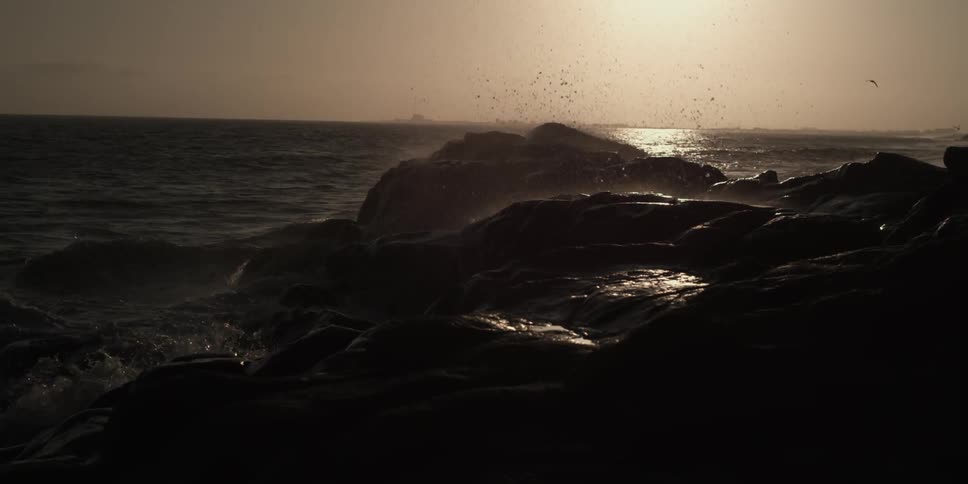 Waves splash up onto the rocks at sunset