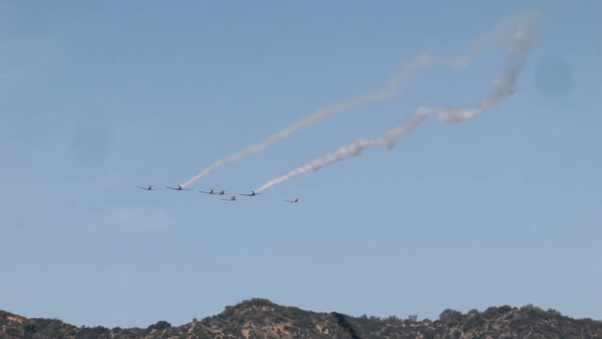 A row of planes are leaving a trail of smoke in the sky