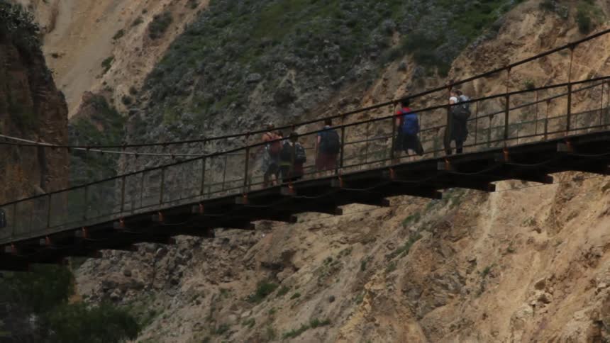 People walk across a suspension bridge