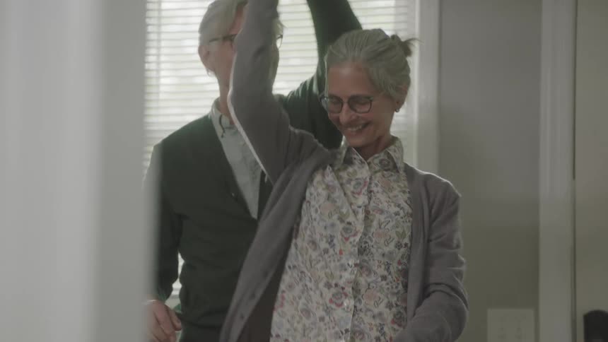 Elderly couple dance and embrace in living room