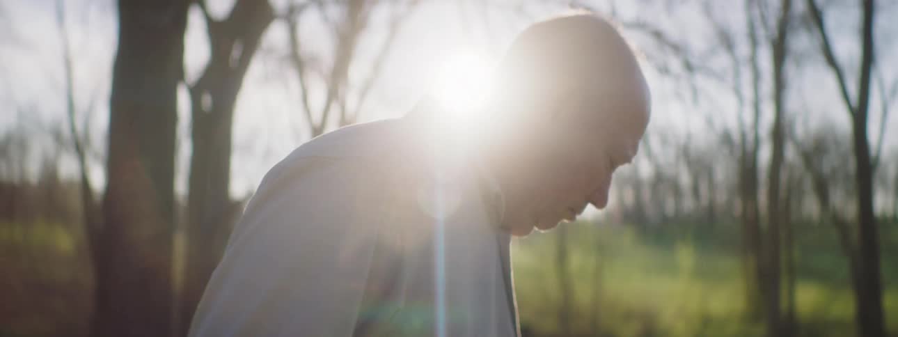 Bald man stands outside looking distressed