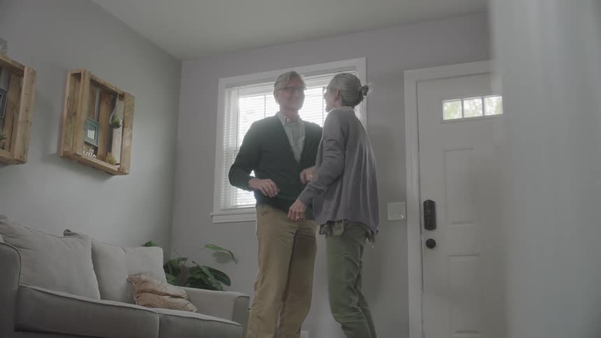Elder couple dancing and hugging in living room enjoying the moment