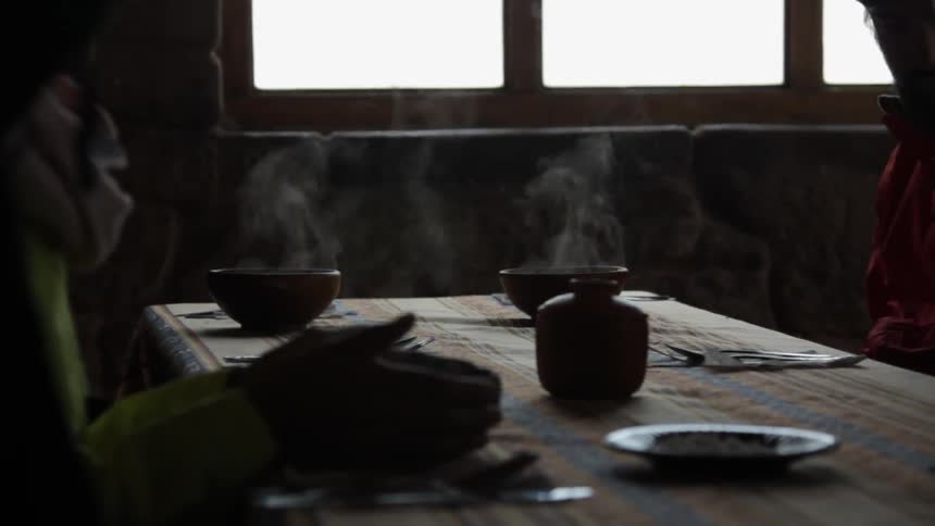 A person is sitting at a table with bowls that are steaming