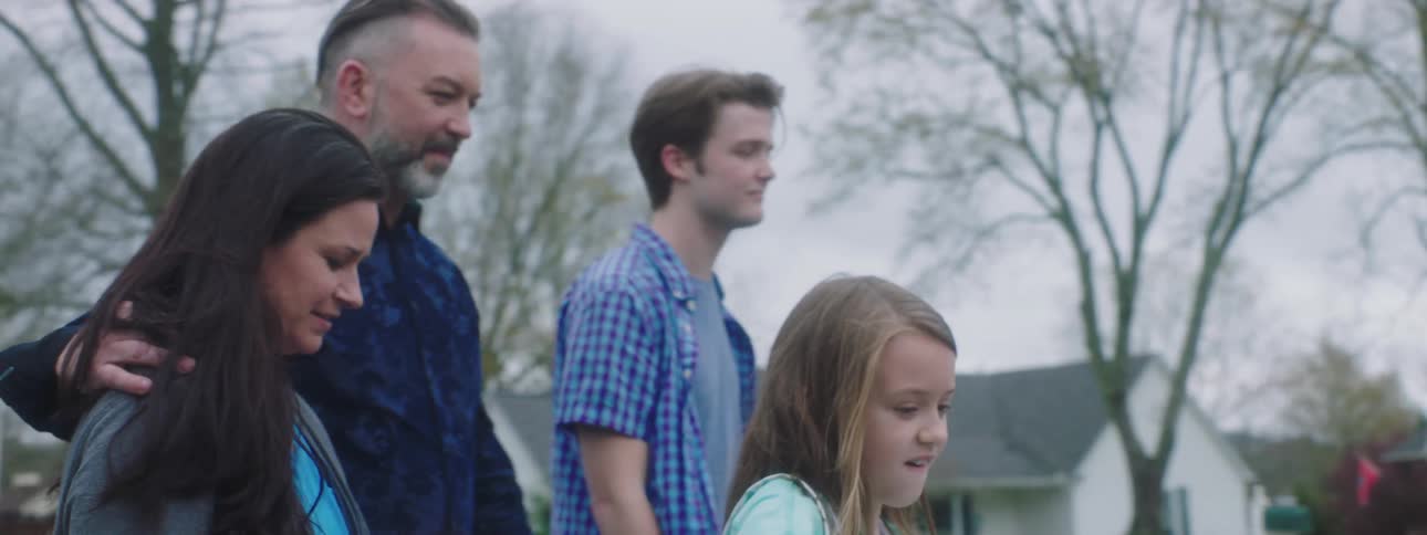 A family walks together on a suburban roadway