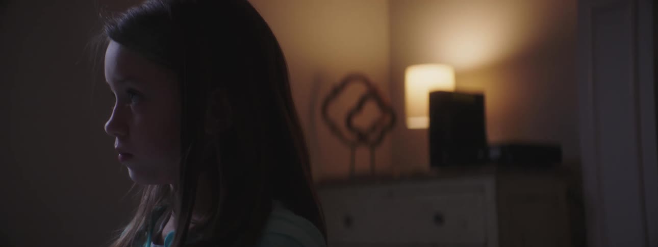 Little girl looks down and up in a dim lit room at night