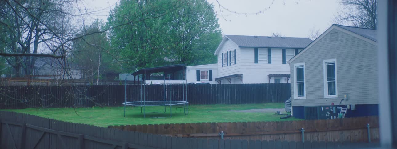A trampoline in an empty backyard on a rainy day