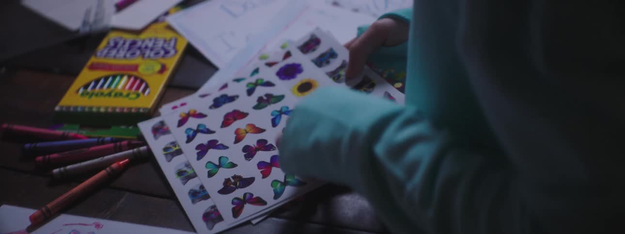 Kid uses butterfly stickers with crayons on homework