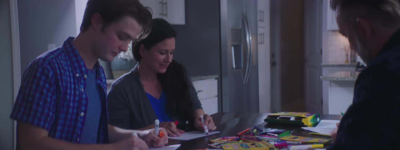 Family sits on kitchen table to make handwritten signs on paper